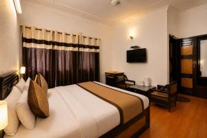 a hotel room with a bed and a desk and a television at Hotel Arina in Chandīgarh