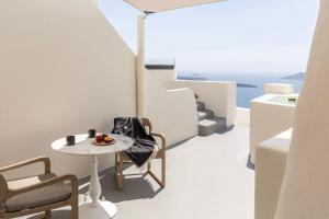 a table and chairs in a room with a view of the ocean at Istoria, a Member of Design Hotels in Perivolos