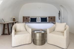 a bedroom with a bed and two chairs at Istoria, a Member of Design Hotels in Perivolos