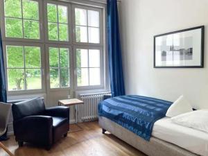 a bedroom with a bed and a chair and windows at Hotel Wagner im Dammtorpalais in Hamburg