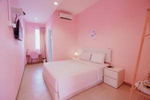 a bedroom with a white bed and a pink wall at Hugstore Pink Hotel in George Town
