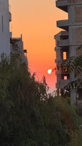 a sunset behind some buildings and some grass at Loutraki Sea Breeze Sunset Apt in Loutraki +18 photos