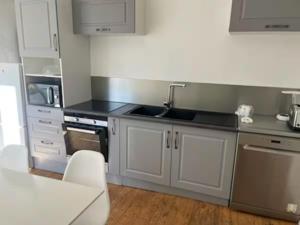 a kitchen with white cabinets and stainless steel appliances at Tout confort T2 in La Bourboule