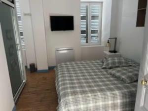 a bedroom with a bed and a tv on the wall at Tout confort T2 in La Bourboule