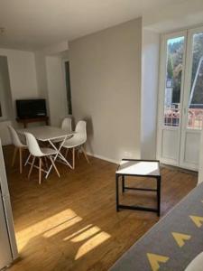 a living room with a table and chairs in a room at Tout confort T2 in La Bourboule