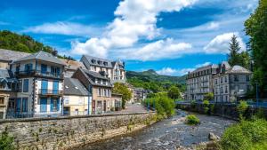 a town in the mountains with a river and buildings at Tout confort T2 in La Bourboule +5 photos