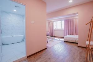 a bathroom with a bath tub and a bedroom at Hugstore Pink Hotel in George Town