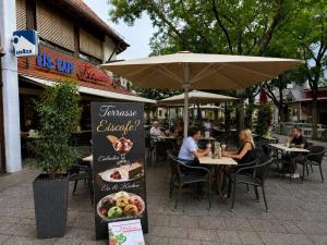 a group of people sitting at a restaurant under an umbrella at Hotel Garni Italia in Bühl