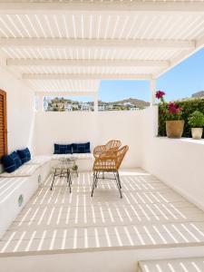 a white patio with two chairs and a table at Patmos Sunshine Houses - Quiet Stay, 5-min Walk to Skala Square in Patmos