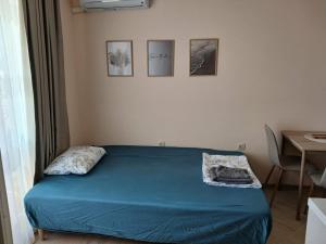 a bedroom with a bed with blue sheets and a table at Sea&Sunset Studio in Sozopol +12 photos