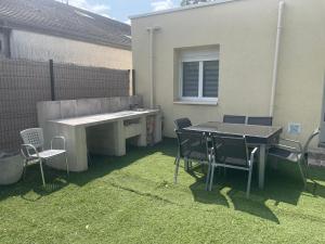 a patio with a table and chairs on the grass at Maison moderne proche CDG in Aulnay-sous-Bois