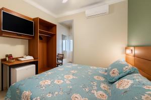 a bedroom with a bed with a blue comforter and a television at Hotel Nova York in Araçatuba