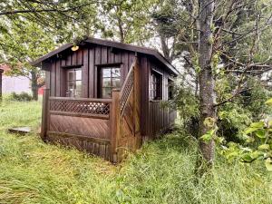 a small wooden building in the grass next to a tree at Egilsstadir 1, Skógarkot, Urridafossvegur, Selfoss in Selfoss