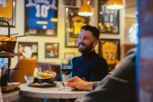a man sitting at a table with a glass of wine at Urban Hotel & Spa Aix-les-Bains - BW Signature Collection in Aix-les-Bains