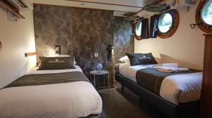 a bedroom with two beds and a stone wall at Passengerschip Princesse Royal in Groningen