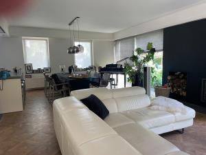 a living room with a white couch and a piano at TML Music Guesthouse in Aartselaar