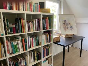 a book shelf filled with books next to a table at TML Music Guesthouse in Aartselaar