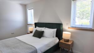 a bedroom with a bed with a green headboard and two lamps at Birch Tree Lodge - Luxurious Lodge on the NC500 by Thrumster Lodges in Wick