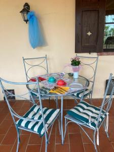 a glass table with two chairs and a table with a bowl of flowers at B&B la boffalora in Zaffignano