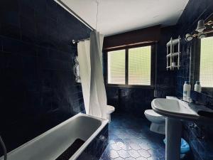 a bathroom with a tub and a toilet and a sink at Pension Casín in Ribadesella