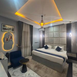 a hotel room with a bed and a blue chair at Classy Castle Hotel And Suite in Ughelli +9 photos