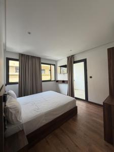 a bedroom with a large white bed and windows at Nezha Hotel in Tangier