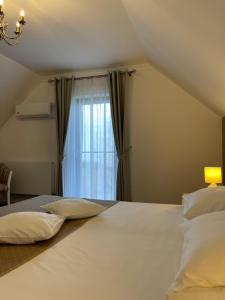 a bedroom with a large white bed with a window at Complex Turistic Comoara Bucovinei in Corlata +125 photos