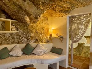 a couch in a room with a rock wall at La Cueva De Orel in Molinicos