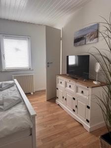 a bedroom with a bed and a television on a dresser at Ferienhaus Fehmarnliebe in Fehmarn