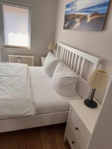 a bedroom with a bed with white sheets and pillows at Ferienhaus Fehmarnliebe in Fehmarn