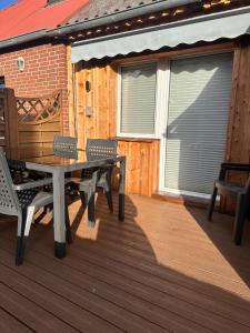 a patio with a table and chairs on a deck at Ferienhaus Fehmarnliebe in Fehmarn