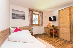 a bedroom with a bed and a desk and a television at Haus Alpenrose in Serfaus