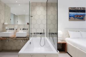 a bathroom with a tub and two sinks and a bed at VISIONAPARTMENTS Berlin - self check-in in Berlin