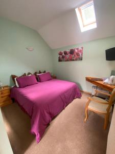 a bedroom with a large pink bed and a desk at Willow Tree Cottages in Newark-on-Trent
