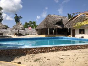 a resort with a swimming pool and a thatched building at Nanakizilodge in Mtendeni