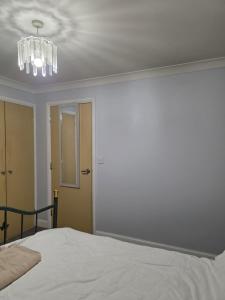 a bedroom with a white bed and a chandelier at Near recreation park in Colchester