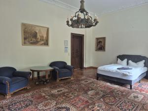 a bedroom with a bed and chairs and a chandelier at PP Pension Potsdam in Potsdam