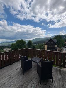 a patio with two chairs and a table on a deck at Dzikie Fiołki in Karpacz