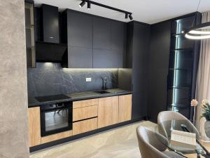 a kitchen with black walls and wooden cabinets at NOVA Olimpia Residence - Free Garage in Sarajevo +10 photos