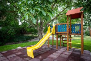a playground with a yellow slide in a park at Diófa Vendégház in Békésszentandrás