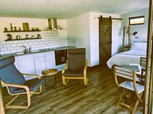 a bedroom with a bed and a kitchen with two chairs at An Garraí Mór in Omagh