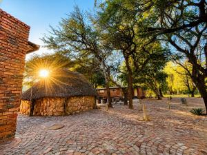 a brick building with a thatch roof and trees at Lake Cabin in Olifantshoek