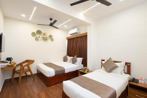 a hotel room with two beds and a desk at FLY VIEW Airport Residency in Nedumbassery +104 photos