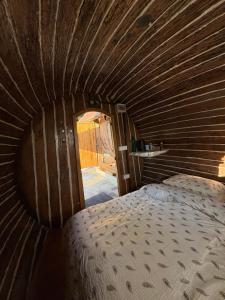 a bed in a room with a wooden ceiling at Glamping Medvedjek - Nočitev v vinskem sodu in Velika Loka