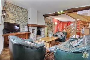 a living room with leather furniture and a stone fireplace at Les hauts de kergiquel in Paimpol