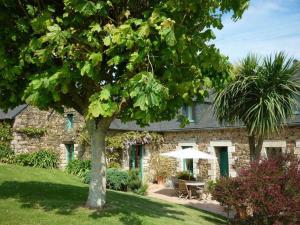 a stone house with a table and an umbrella at Les hauts de kergiquel in Paimpol