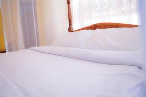 a close up of a bed with white sheets and a window at Stardom Hotel in Nairobi