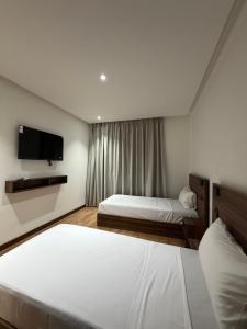 a hotel room with two beds and a flat screen tv at Nezha Hotel in Tangier +13 photos