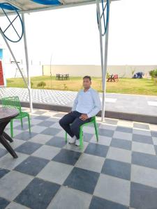 a man sitting on a green chair on a checkered floor at The Pool place and Restaurant in Bagar Meo +7 photos
