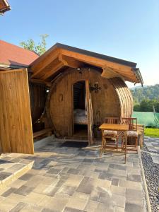a wooden house with a table and chairs in it at Glamping Medvedjek - Nočitev v vinskem sodu in Velika Loka